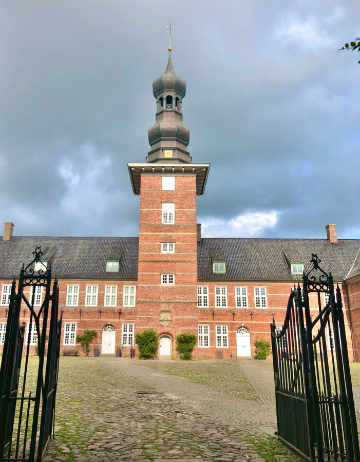 Das Schloss vor Husum ragt hinter einem geöffneten, schwarzen Eisentor hoch auf