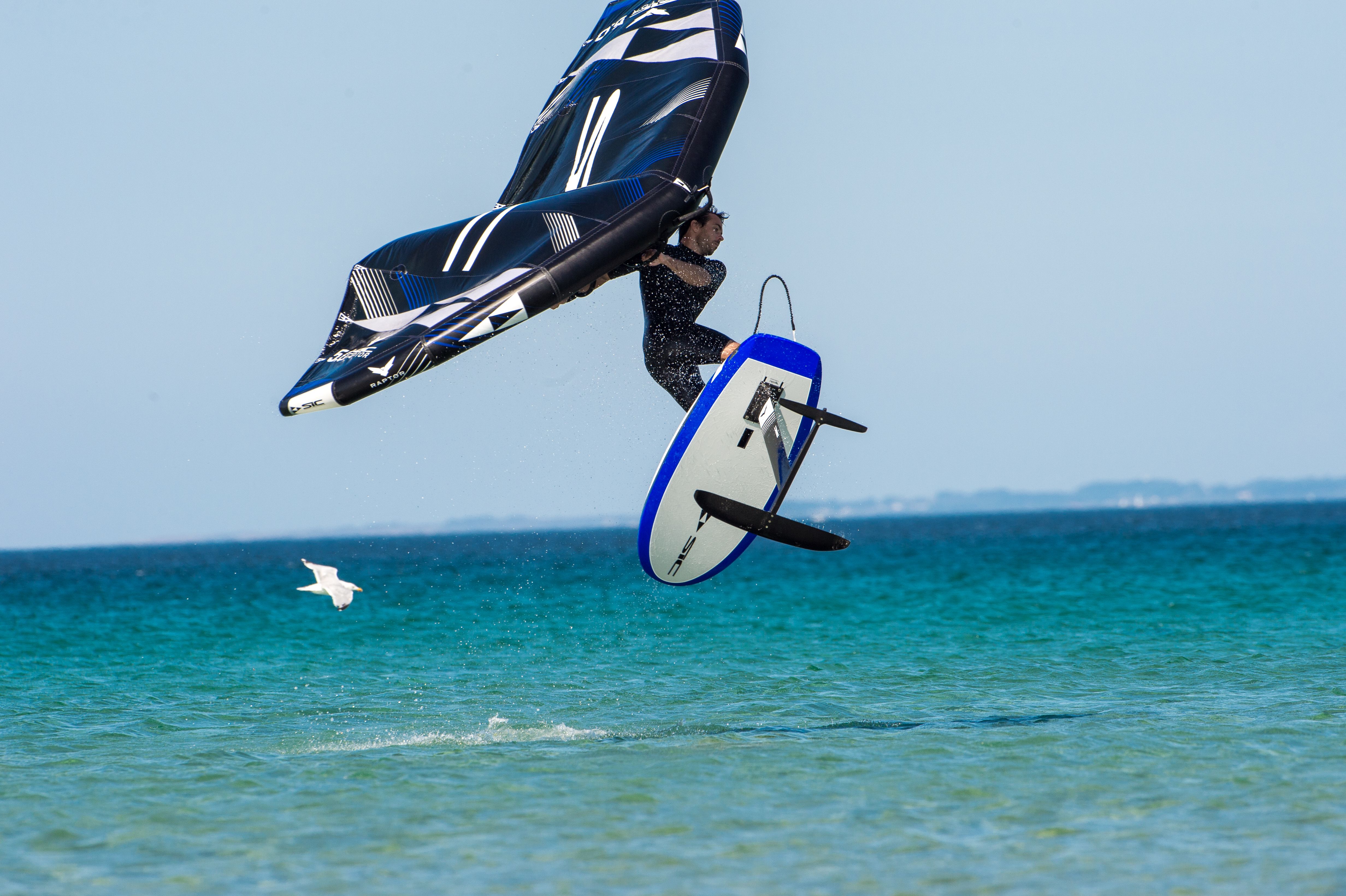 Ein Wassersportler fliegt mit seinem Wingfoil über das Wasser